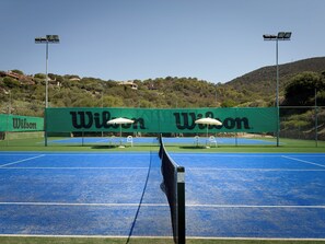 Un terrain de tennis avec un filet, deux chaises et une banderole ornée du logo Wilson.