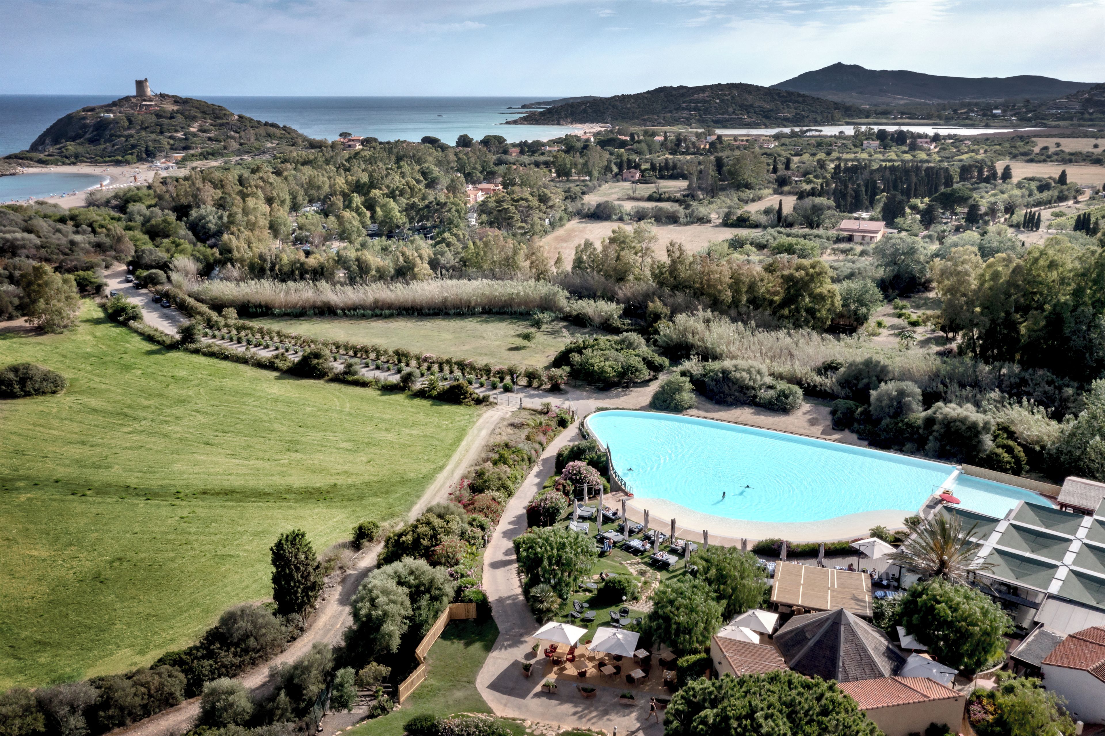 Ein großer Pool, umgeben von üppiger Vegetation mit Blick aufs Meer.