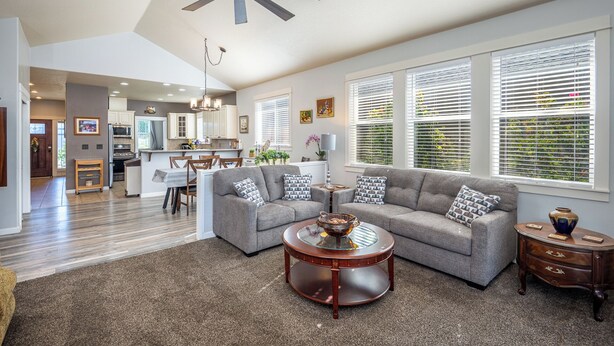 Ein geräumiges Wohnzimmer mit grauem Sofa, einem Couchtisch und einem Deckenventilator.