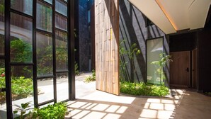 Een modern gebouw met grote glasramen, een houten lamellenwand en een betonnen vloer met schaduwen.