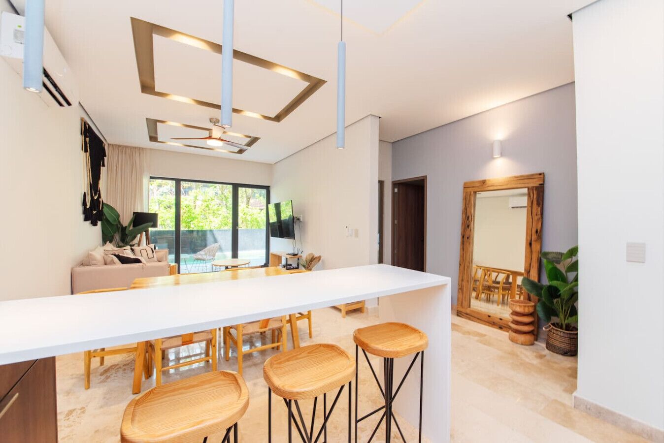 A modern kitchen with a central island, bar stools, and a dining area with chairs.
