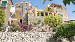 Um edifício de pedra com varanda e parede de pedra à frente.