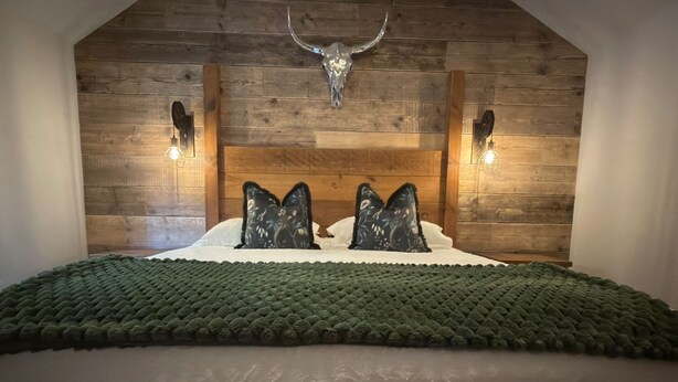 A bedroom with a wooden headboard, two wall-mounted lights, and a decorative skull.