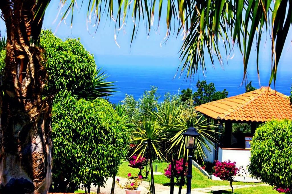 Um jardim costeiro com um gazebo, vegetação exuberante e vista para o mar.
