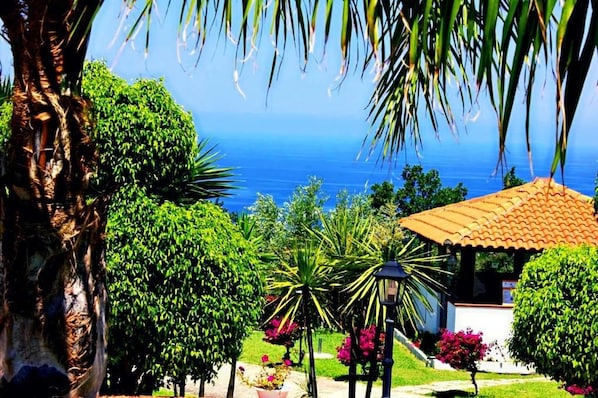 Ein Küstengarten mit einem Gartenpavillon, üppigem Grün und Blick aufs Meer.