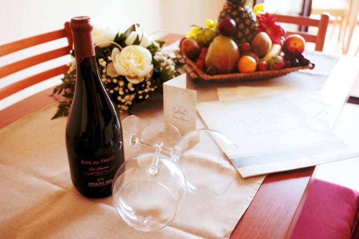 A bottle of wine, two wine glasses, a fruit basket, and a card on a table.