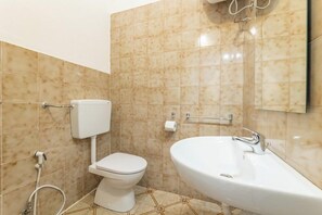 Une salle de bain avec des toilettes, un lavabo et des murs carrelés.