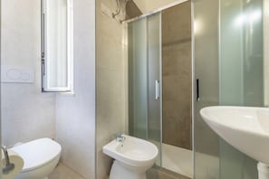 Une salle de bain moderne équipée de toilettes, d’un bidet et d’une douche à parois de verre.