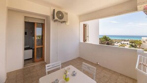 Un balcon avec une table dressée pour deux personnes, une porte coulissante et une vue sur la mer.