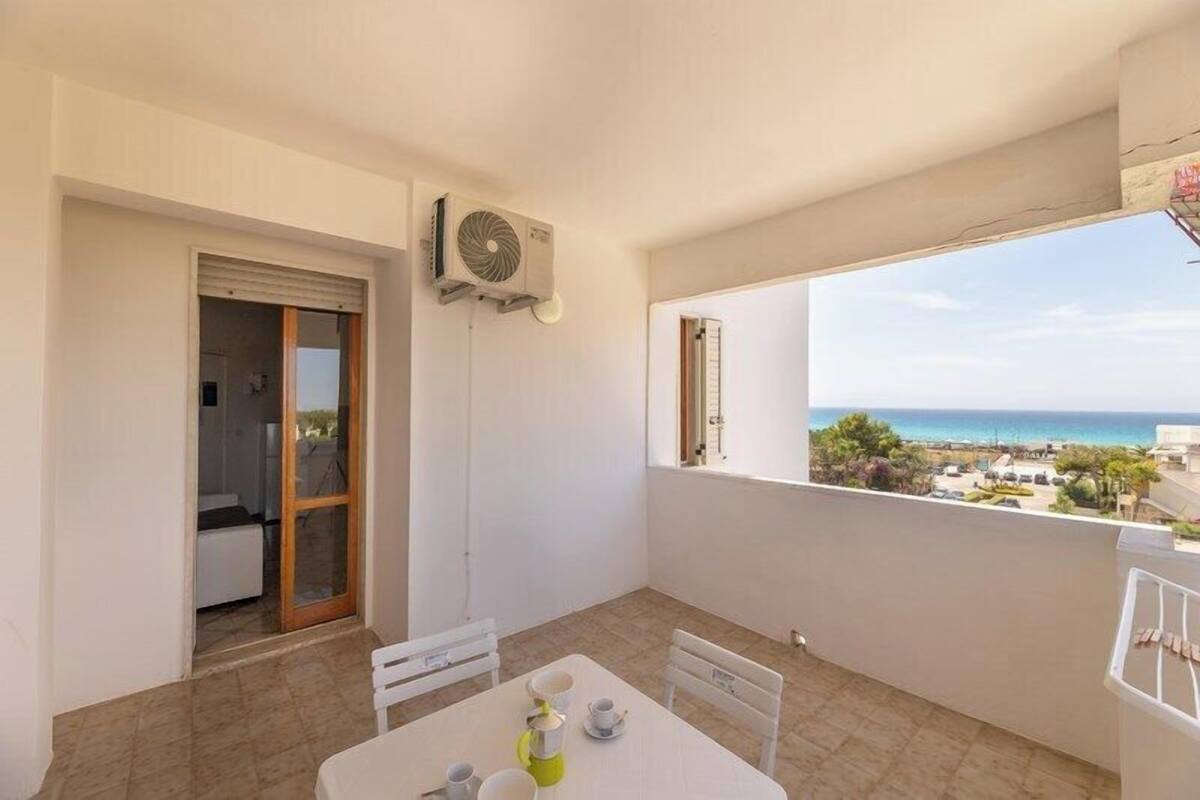 Ein Balkon mit Tisch für zwei Personen, einer Schiebetür und Blick aufs Meer.