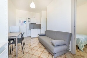Un espace de vie compact comprenant un coin cuisine, un coin repas et un canapé.