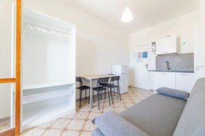 Ein kompakter Raum mit Bett, Küchenzeile, Essbereich und Kleiderschrank.