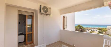 A balcony with a table set for two, a sliding door, and a view of the sea.