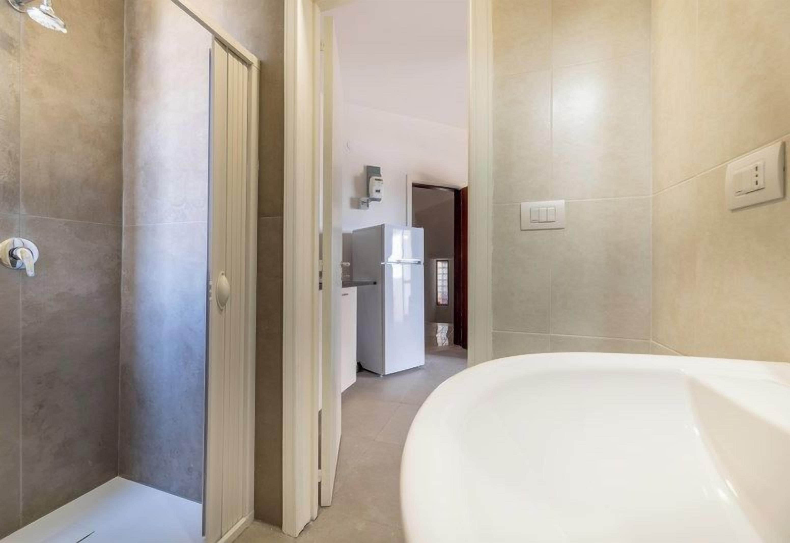 Un baño con ducha, inodoro y lavamanos. Hay una puerta que da a otra habitación.