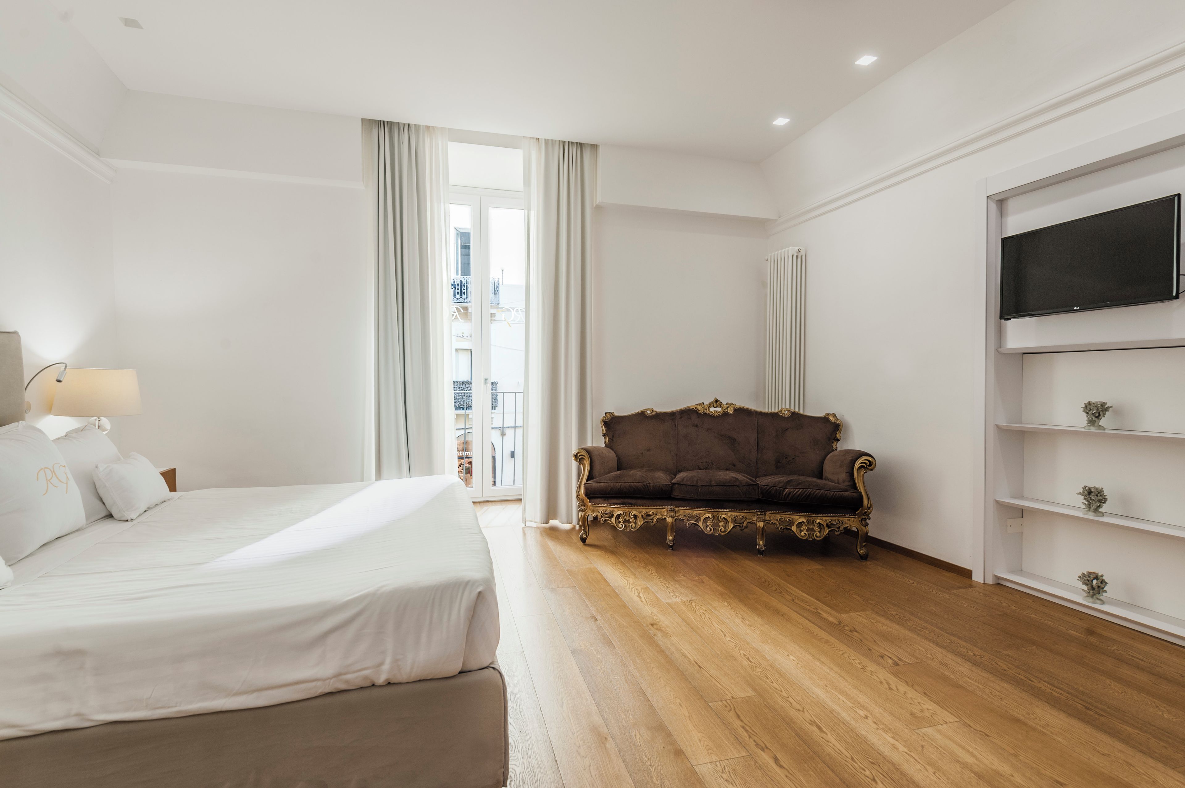 Camera d'albergo con un letto, una poltrona, una televisione e vista sull'esterno.