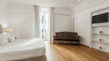 Camera d'albergo con un letto, una poltrona, una televisione e vista sull'esterno.