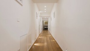 A narrow hallway with wooden flooring, white walls, and recessed lighting. - Rg7 Apartments (Catania)