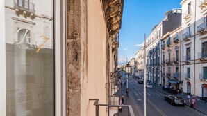 A street view with buildings, a car, and pedestrians. - Rg7 Apartments (Catania)