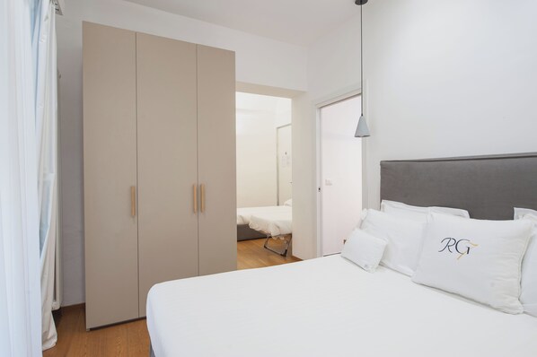 A bedroom with a bed, a wardrobe, and a door leading to another room.