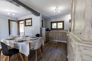 Ein Essbereich mit einem Tisch für vier Personen, eine Küche mit Holdekor und ein Fenster, das für natürliches Licht sorgt.