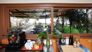 Un comptoir de cuisine donnant sur un espace de restauration extérieur, visible à travers une fenêtre.
