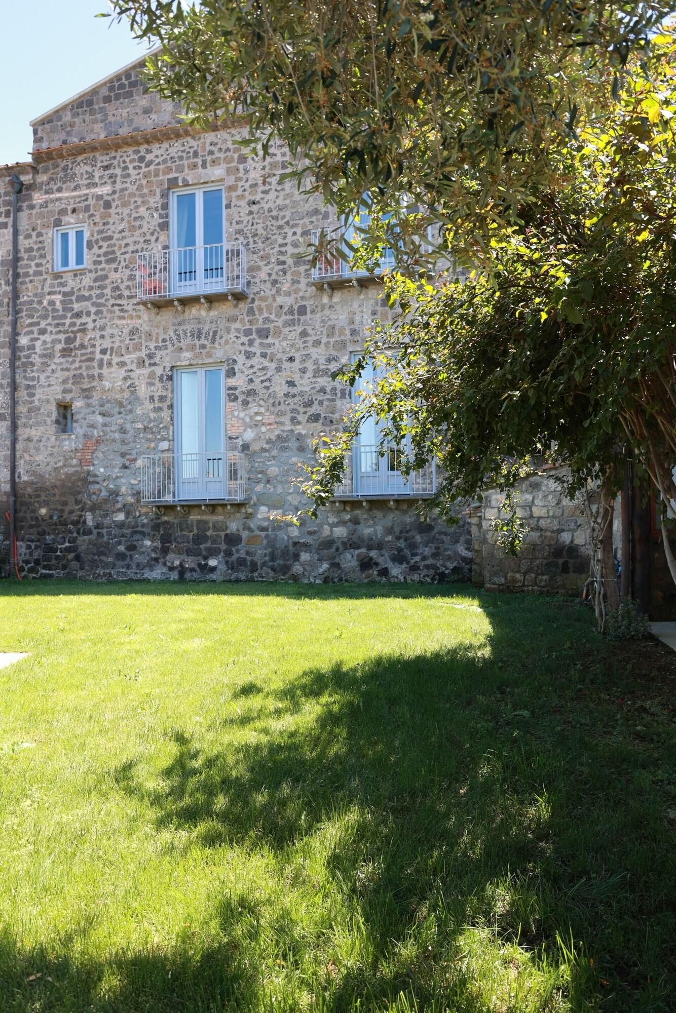 Un bâtiment en pierre avec une cour verdoyante et un arbre.