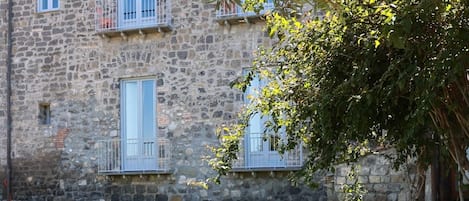 Un bâtiment en pierre avec une cour verdoyante et un arbre.