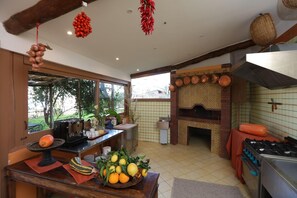 Uma cozinha com forno de tijolos, fogão e área de jantar com mesa posta para dois.