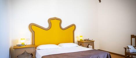 A hotel room with a large bed, two bedside tables, a nightstand, and a mirror.