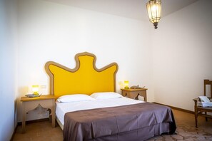 Une chambre d’hôtel avec un grand lit, deux tables de chevet, une petite table et un miroir.