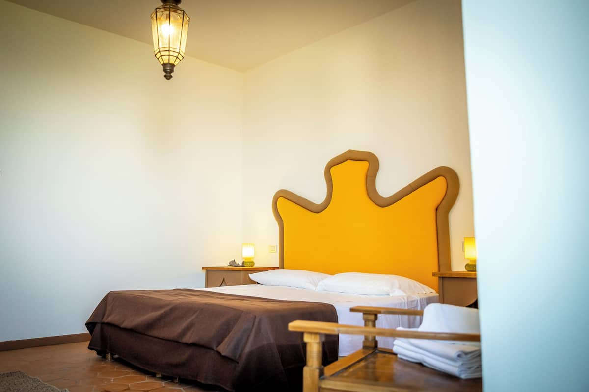 Une chambre à coucher avec un grand lit, une tête de lit en bois, une table de chevet avec une lampe et une chaise.