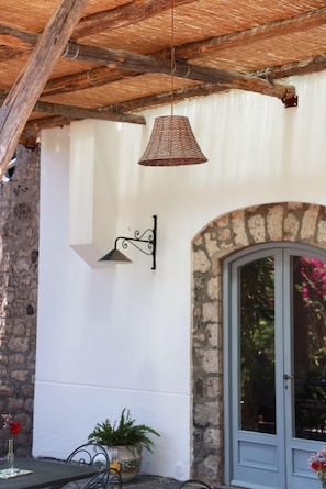 A building with a stone facade, a metal door, and a hanging wicker lamp.