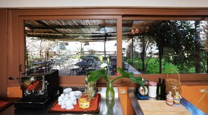 A kitchen counter with a view of an outdoor dining area through a window. - Villa Puolo - With Private Sea Access (Sorrento)