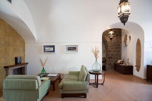Amplia sala de estar con chimenea, mobiliario tapizado en verde y una pared de piedra.