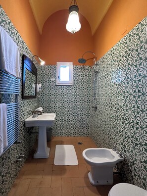 A bathroom with patterned tiles, a sink, a bidet, a mirror, and a towel rack. - Villa Puolo - With Private Sea Access (Sorrento)
