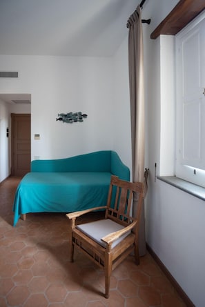 Une pièce avec un canapé de couleur turquoise, une chaise en bois, une porte blanche et une décoration murale représentant des poissons.