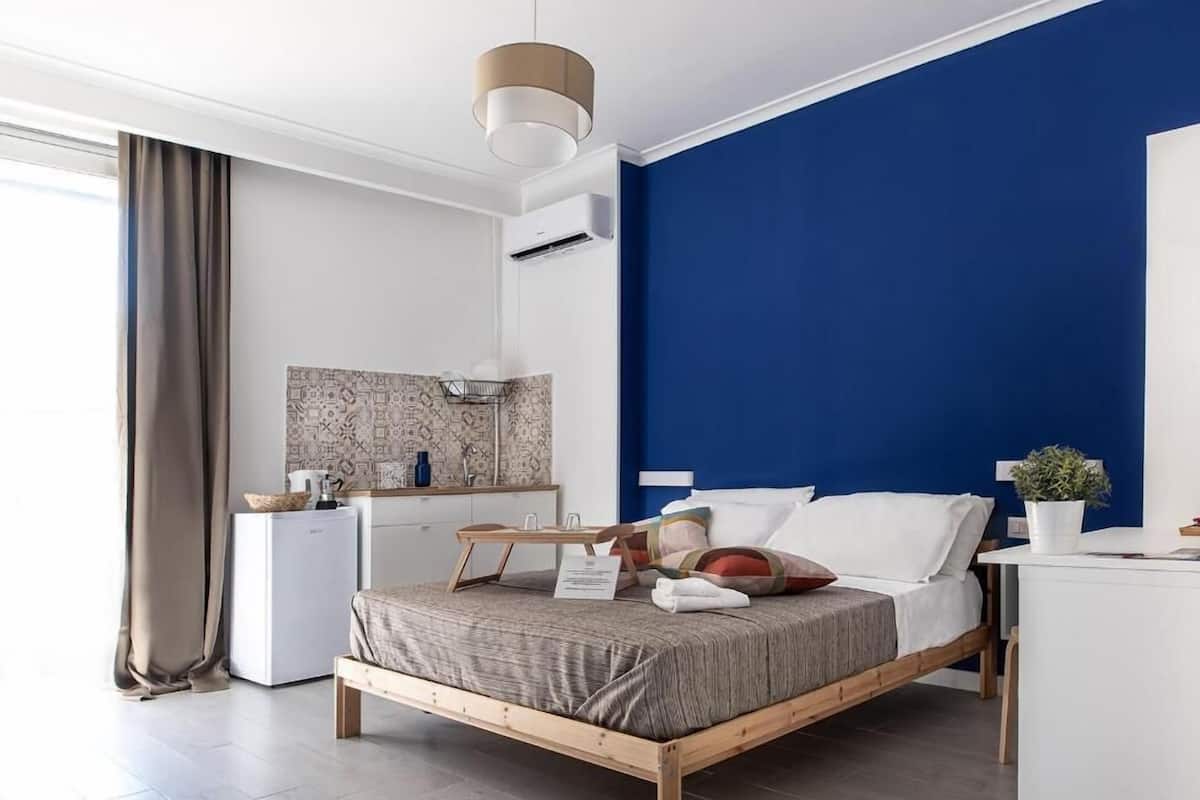A modern bedroom with a wooden bed, a white desk, and a blue accent wall.