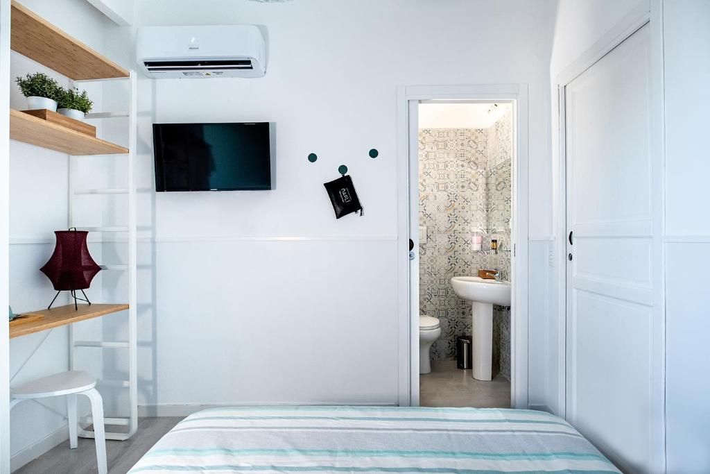 Ein gemütliches Schlafzimmer mit Bett, Fernseher, Schreibtisch mit Stuhl und Kleiderschrank.