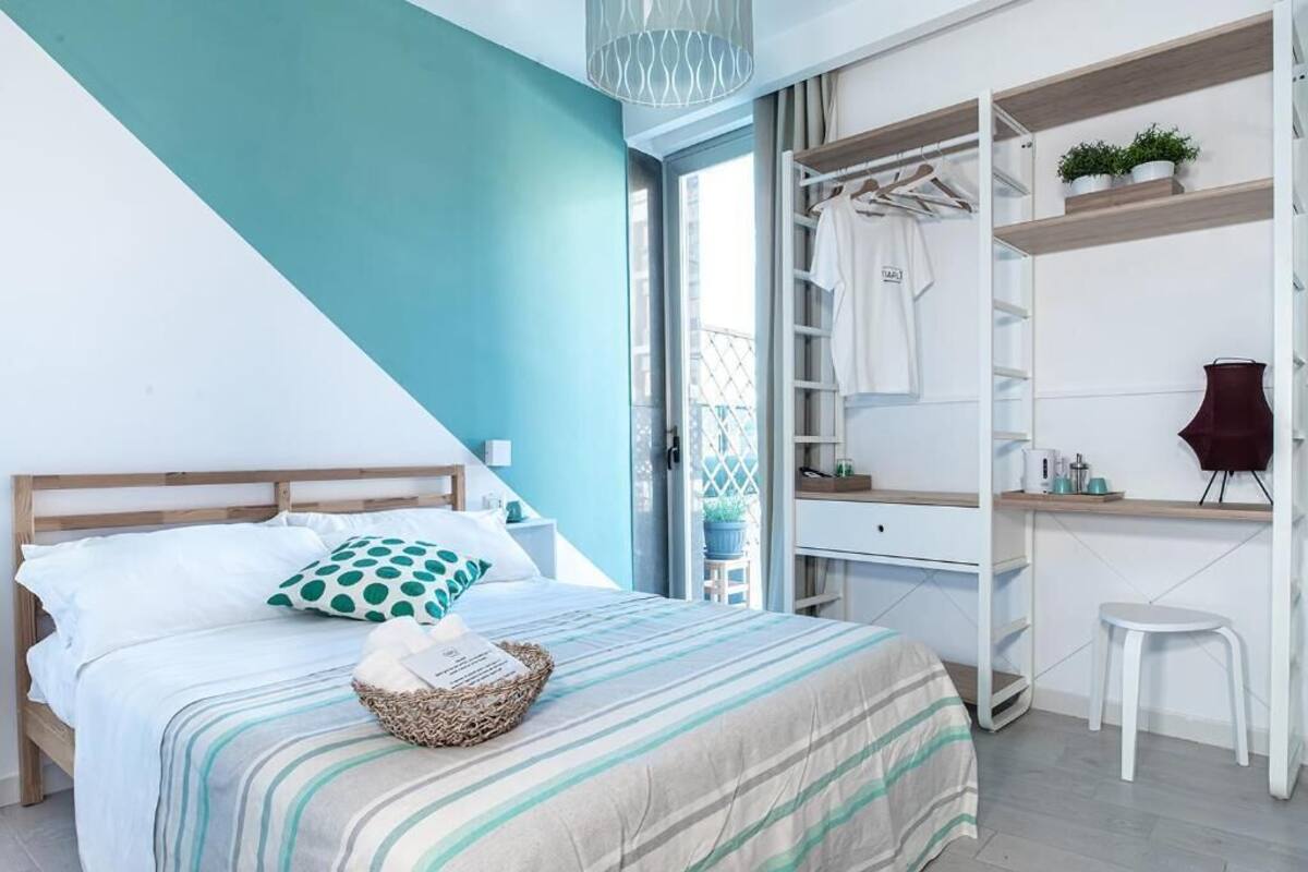 A bedroom with a bed, a bedside table, a wardrobe, and a small stool.