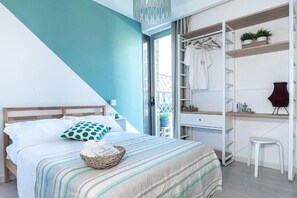 A bedroom with a bed, a bedside table, a wardrobe, and a small stool. - P.c. Boutique H. Sea View (Naples)