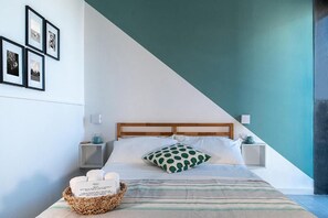 A bedroom with a bed, a nightstand, a bedside table, a wall-mounted shelf, and a framed picture on the wall. - P.c. Boutique H. Sea View (Naples)