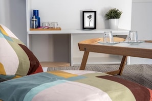 A cozy room with a colorful quilted bedspread, a wooden table with clear glassware, a framed picture on the wall, and a small potted plant. - P.c. Boutique H. Sea View (Naples)