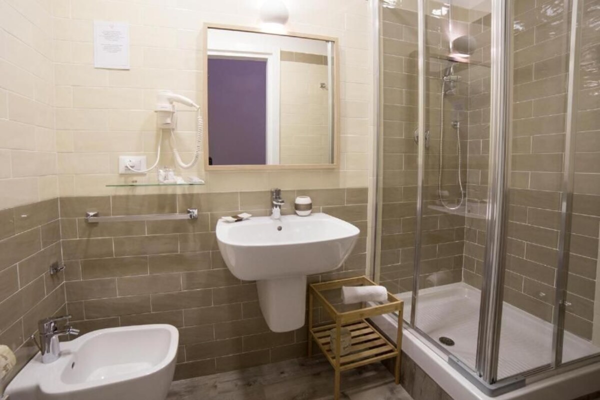 A bathroom with a sink, mirror, and shower.