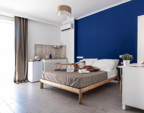 A modern hotel room with a bed, bedside table, and a small kitchenette. - P.c. Boutique H. Sea View (Naples)