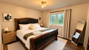 Un dormitorio con cama, mesita de noche, lámpara, ventana y espejo.