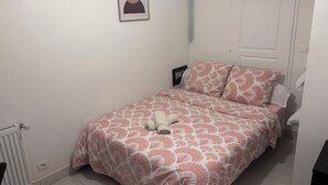 Un dormitorio con cama, radiador, puerta y un cuadro en la pared.
