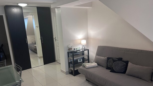 Una sala de estar moderna con un sofá, una mesita de noche con una lámpara, y un comedor con una mesa de vidrio y sillas.