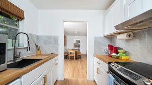 A modern kitchen with white cabinets, a wooden countertop, and a stainless steel range hood.