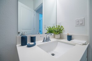 A bathroom with a white sink, a mirror, a potted plant, and a blue soap dispenser. - Escape the Winter! Cozy 3BR Retreat in Sunny Ocala, Florida (Ocala)