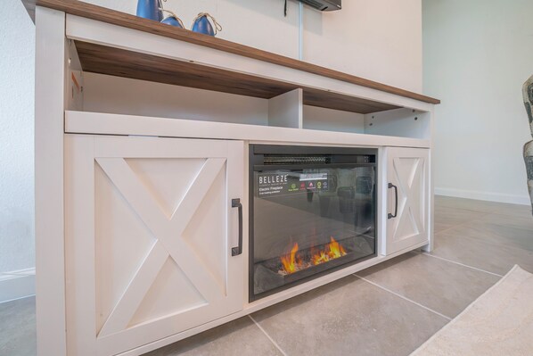 A fireplace with a glass front, white cabinetry, and a wooden shelf above. - Escape the Winter! Cozy 3BR Retreat in Sunny Ocala, Florida (Ocala)